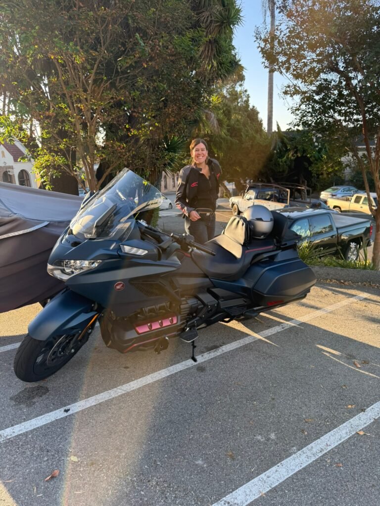 a blue Honda goldwing motorcycle parked with a girl standing next to it
